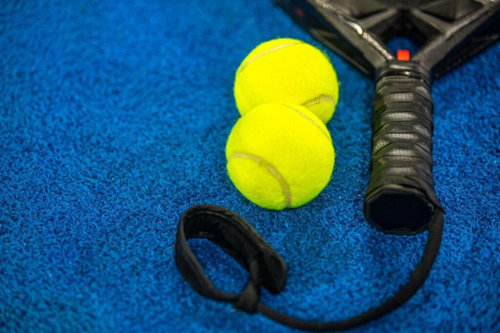 Pala de pádel y pelotas preparadas sobre una pista